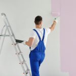 Man,Painting,Wall,With,Light,Pink,Dye,Indoors,,Back,View